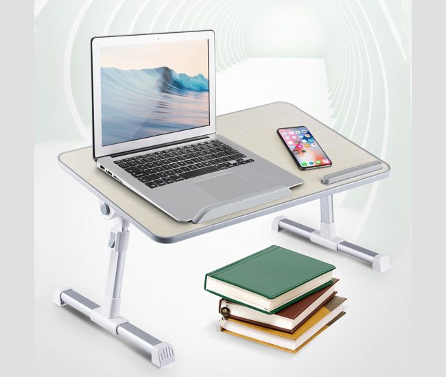 White folding lap desk with adjustable legs set up over a bed