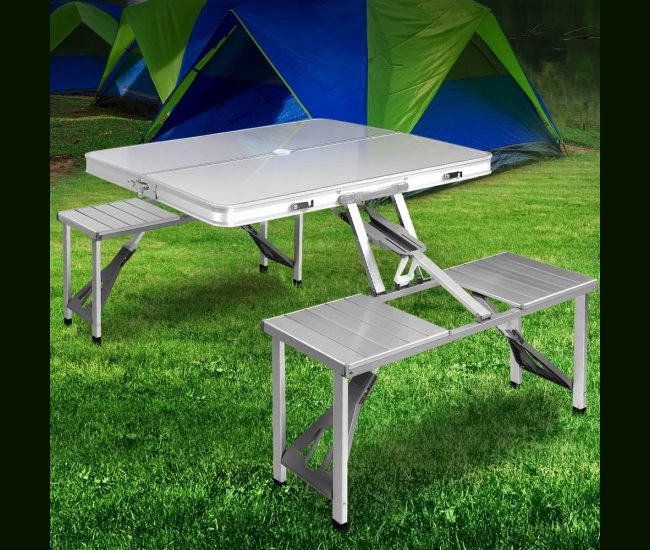 Folding aluminium camping table with four attached seats, set up on grass