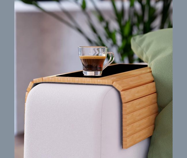 Grey sofa arm tray draped over a couch armrest holding a mug and a phone