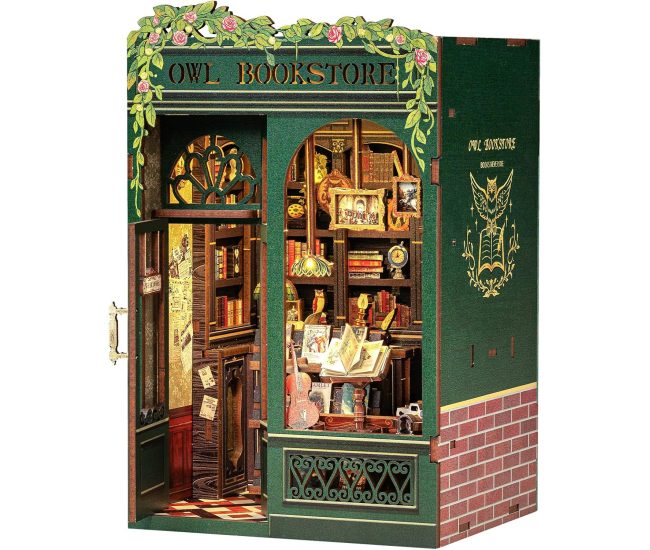 Illuminated miniature bookstore book nook slotted between real books on a shelf