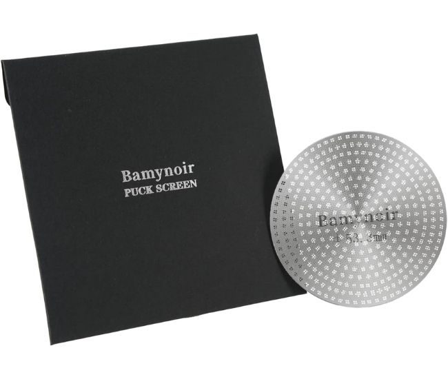 Thin stainless steel espresso puck screen, a perforated 53.3 mm disc beside a portafilter basket